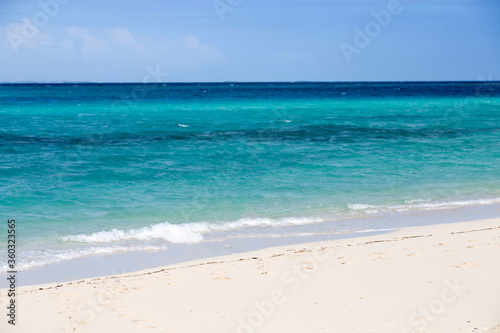 Clean white sand beach with turquoise water . Tropical island background. Small waves crushing on the beach. Clean empty white sand beach on Zanzibar. Small waves crushing on the beach. © Robin