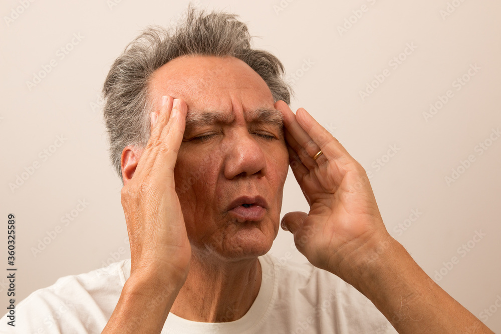 Senior Man in pain with Headache rubbing his temples for relief Senior Man in pain with Headache rubbing his temples for relief