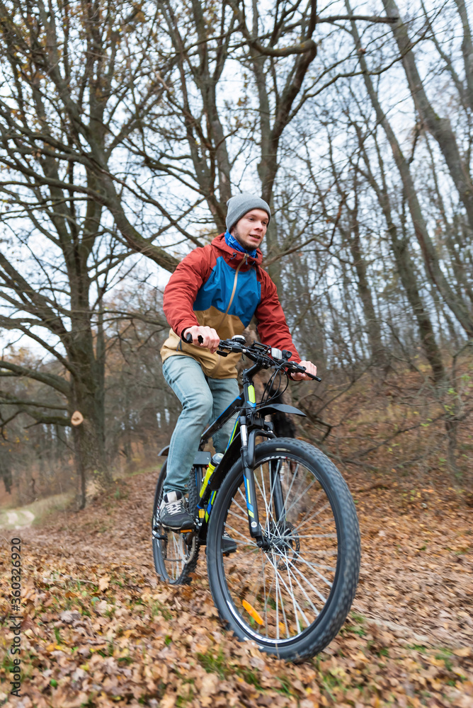 Naklejka premium man rides a bicycle on nature at high speed in autumn