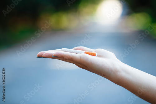 Woman with a cigarette in her hand. Close. Place for text. Smoking cessation concept. Female hand holding a cigarette. © Alex