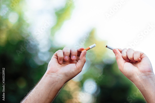 World No Smoking Day. The fight against nicotine addiction. The guy breaks a cigarette. Male hand crushing cigarette. Concept Quitting smoking, World No Tobacco Day. No Smoking.
