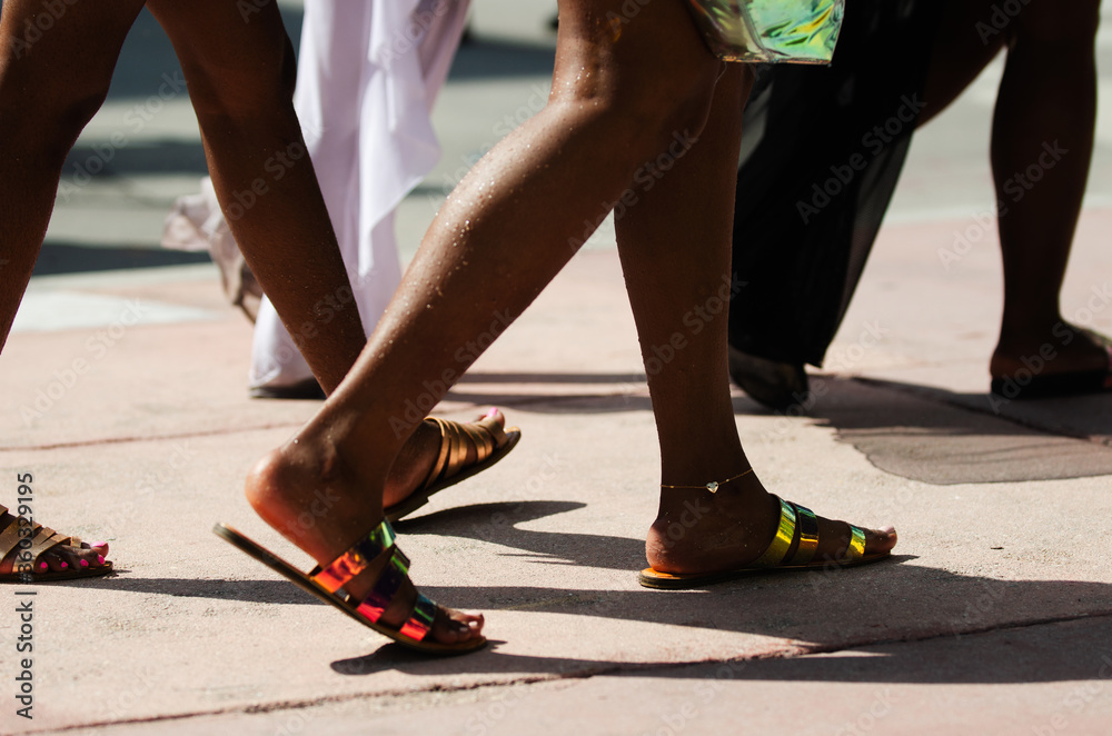 Close-up of unrecognizable young women walking on a sunny summer sidewalk