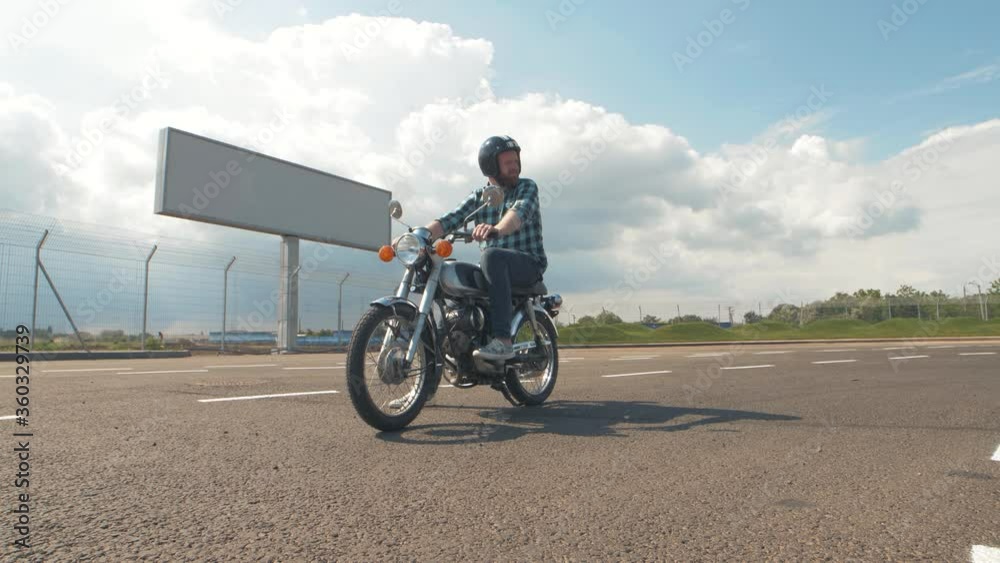Young man biker with custom motorcycle on street at sunset. Male motorcyclist 