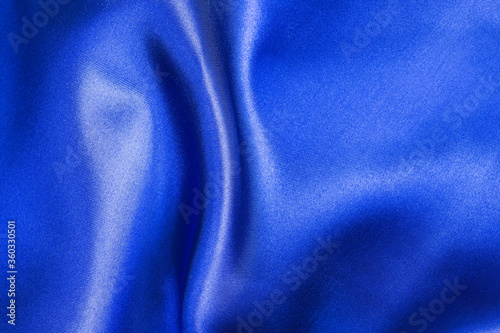 Blue satin fabric with smooth folds. Plain satin texture. Abstract background of luxury satin textile