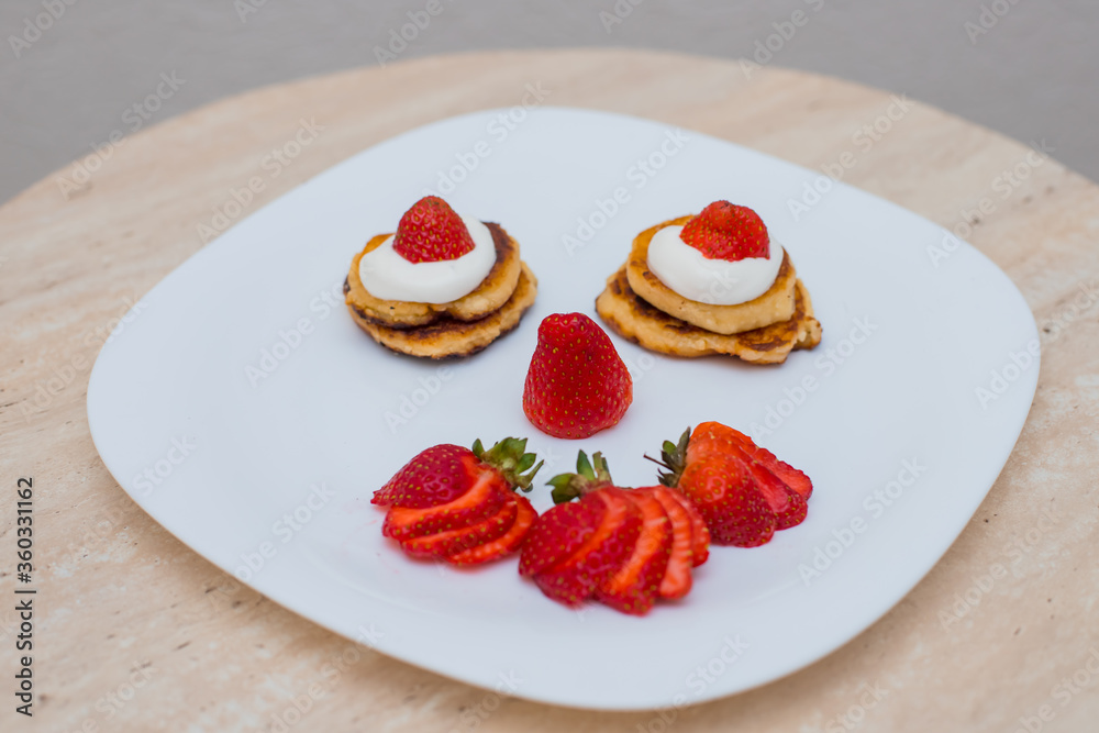 Delicious homemade pancakes with strawberries on plate on a light background