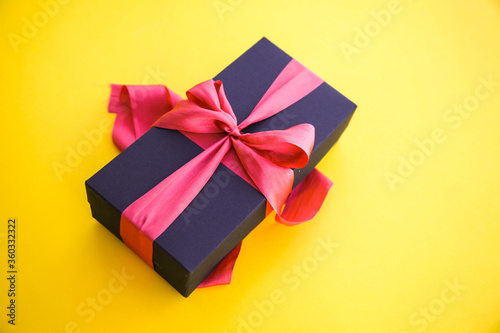 Fototapeta Naklejka Na Ścianę i Meble -  Girl holds a gift box and unties the bow. a girl opens a gift box. Gift box on a red background. Girl unties the tape from the box.
