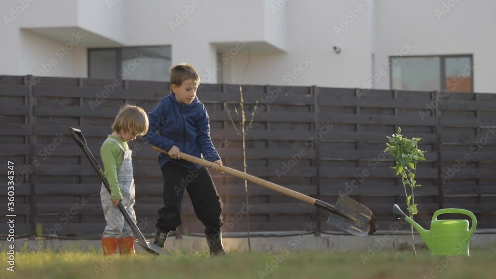 Two children dip together with hoe, working, planting, organic agriculture, early education, cultivate love for work