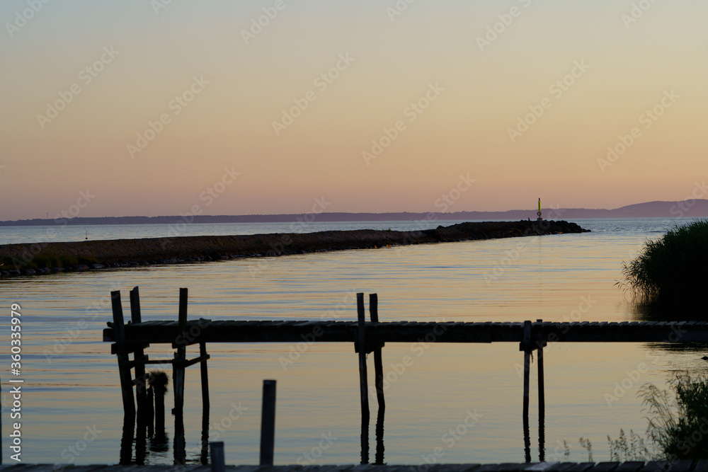 Coastal summer sunset with pier and wooden jetty in Skalderviken, Sweden Coastal summer sunset with pier and wooden jetty in Skalderviken, Sweden