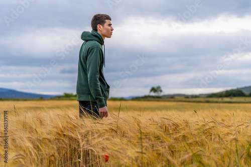 boy in sportswear in a wheat field strolls thoughtfully into the sunset © JuanFrancisco