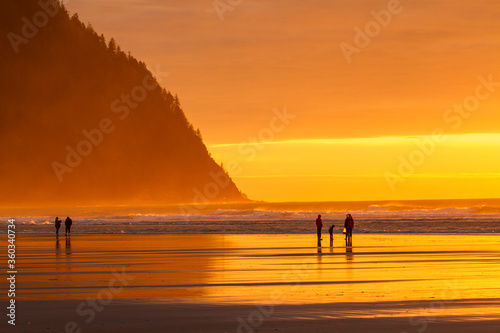 Seaside, Oregon - 2/7/2017: five people, on the beach at sunset at Seside, sunset is reflecting in the wet sand.