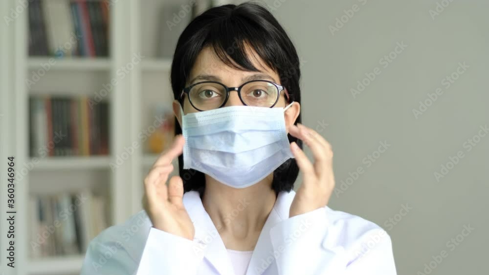 Young adult female doctor wearing face mask close up. Medical protective equipment usage demonstration. Smiling woman portrait. Young adult female doctor wearing face mask close up. Medical protective equipment usage demonstration. Smiling woman portrait.