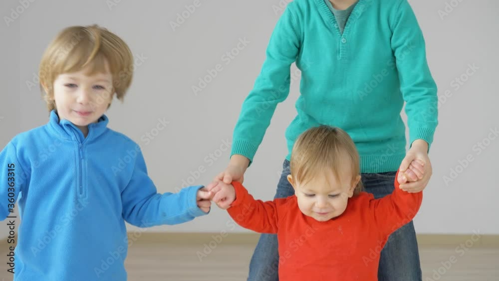 Boys hold baby child brother hands, little kid first step, family support Boys hold baby child brother hands, little kid first step, family support