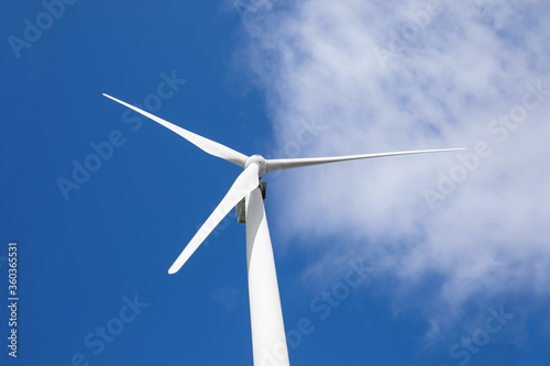 Wind turbine against beautiful blue sky, low angle view. Alternative energy source