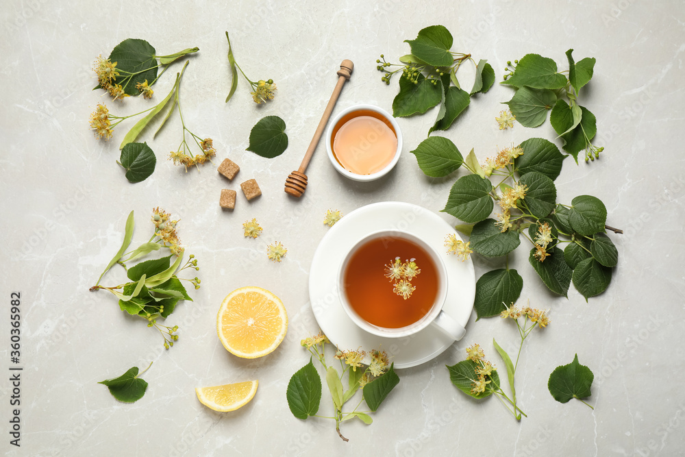 Flat lay composition with tasty tea and linden blossom on light grey marble table Flat lay composition with tasty tea and linden blossom on light grey marble table