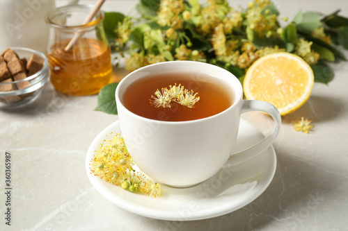 Cup of tea with linden blossom on light grey marble table