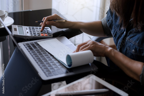 Business woman using calculator and sign cheque at office.