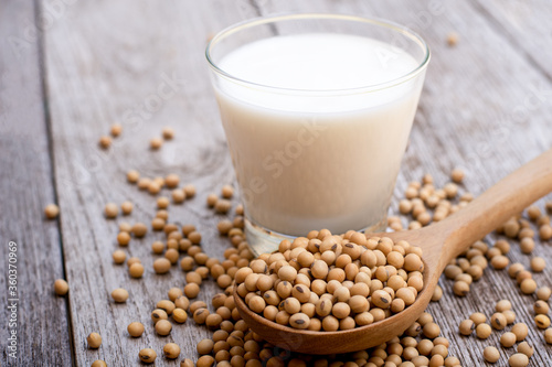 Soy bean in wooden spoon and soy  milk in glass isolated on wood table background.