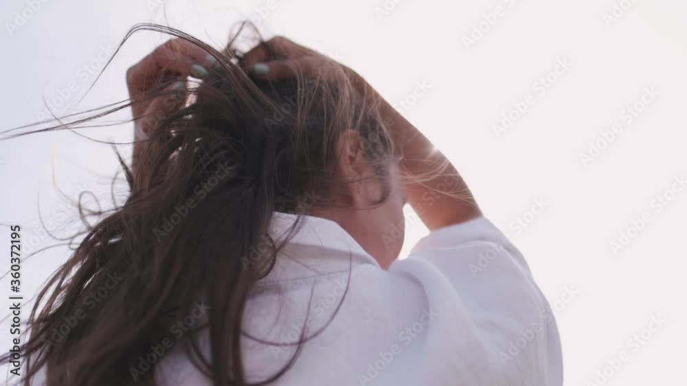 Attractive brunette in a hat and white shirt is enjoying nature in the mountains. hat and hair flying in the wind close-up. hand movement with sunbeams Attractive brunette in a hat and white shirt is enjoying nature in the mountains. hat and hair flying in the wind close-up. hand movement with sunbeams