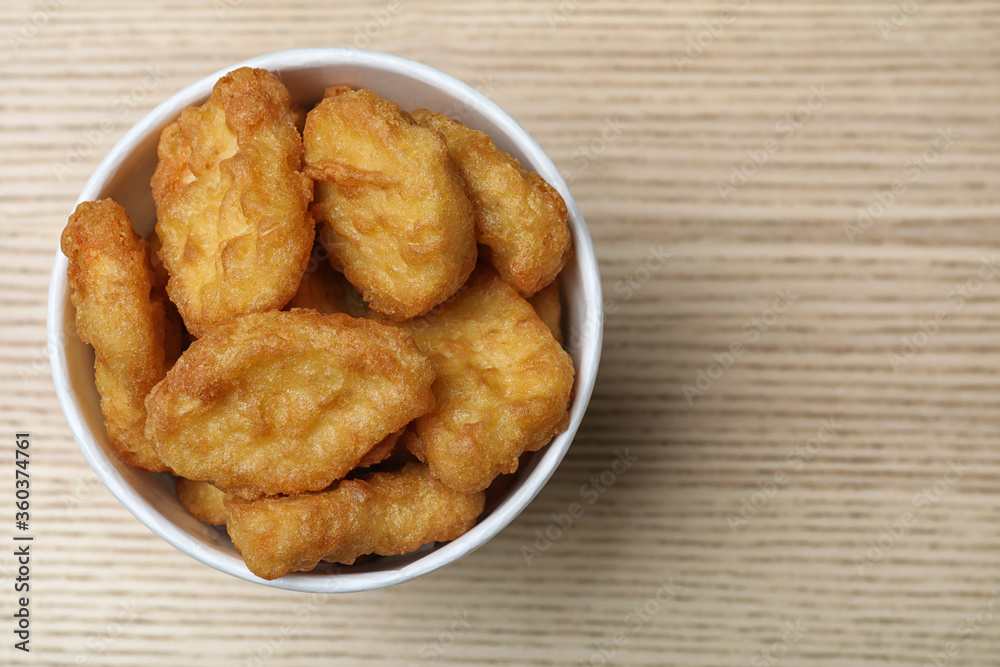 Bucket with tasty chicken nuggets on wooden table, top view. Space for text Bucket with tasty chicken nuggets on wooden table, top view. Space for text