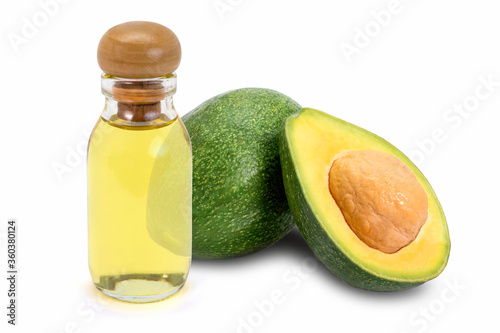 Glass bottle of yellow essential oil extract with whole and half slice of avocado fruit isolated on white background.