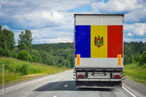 A truck with the national flag of Moldova depicted on the back door carries goods to another country along the highway. Concept of export-import,transportation, national delivery of goods