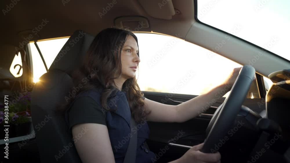 Beautiful brunette woman with long hair driving car at sunset adult woman drives a automobile sun rays shine through car window. Beautiful brunette woman with long hair driving car at sunset adult woman drives a automobile sun rays shine through car window.