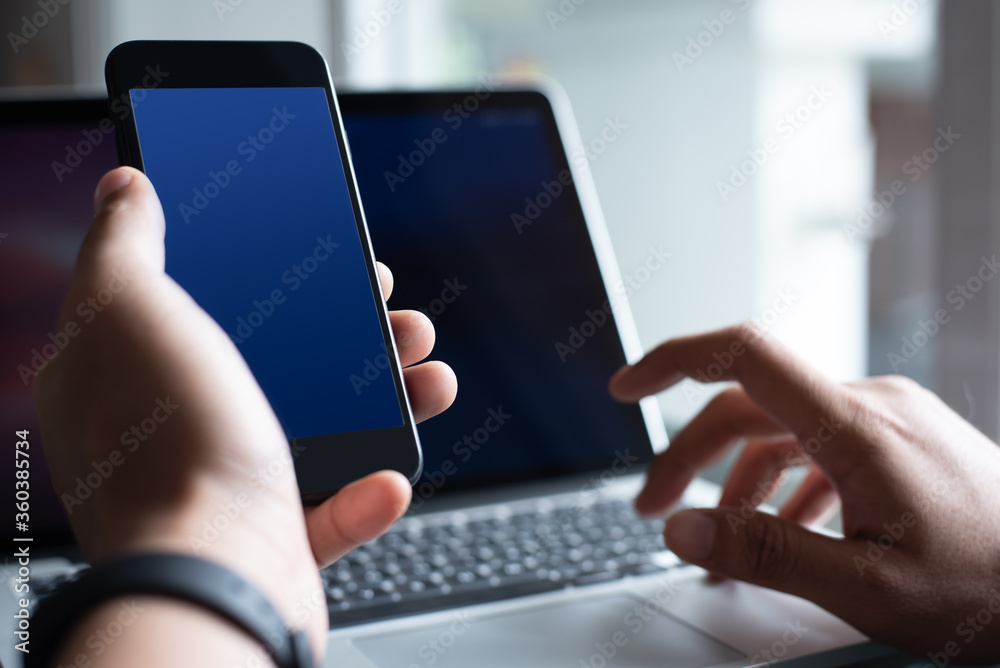 Mockup man using blank blue screen mobile smart phone working in office at office
