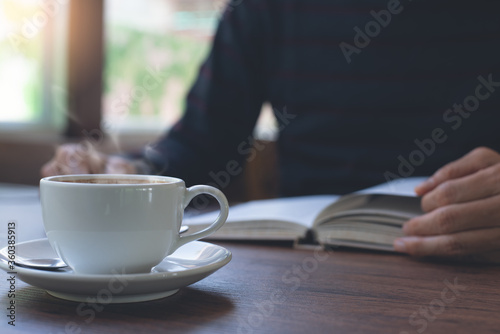 Man reading book with cup of coffee on table at home