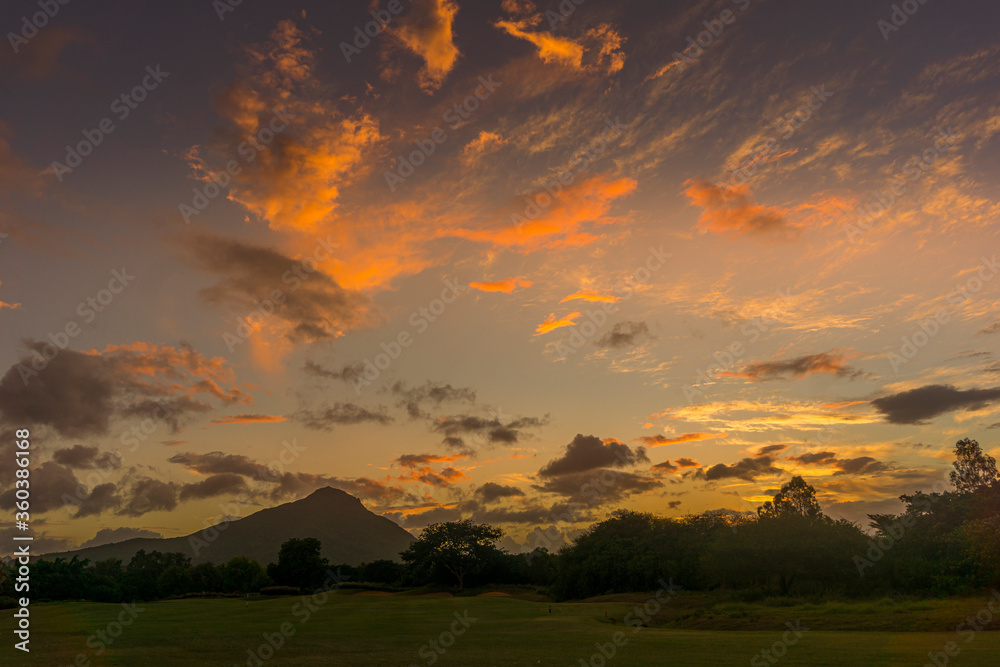 Dramatic sunset sky with beautiful orange clouds over the mountains and woods