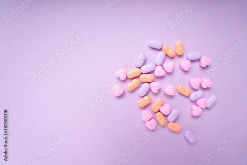 Top view - Pastel colourful vitamin medicine over purple pink background. Messy and seperate.