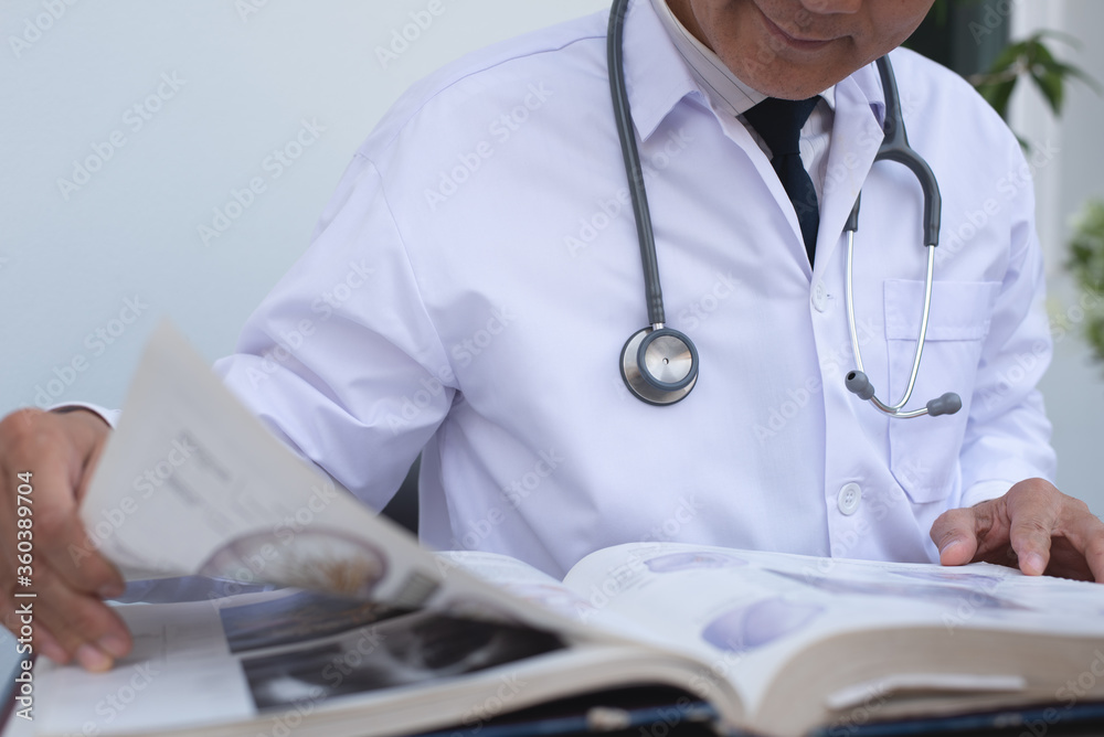 Asian doctor reading medical anatomy text book Asian doctor reading medical anatomy text book