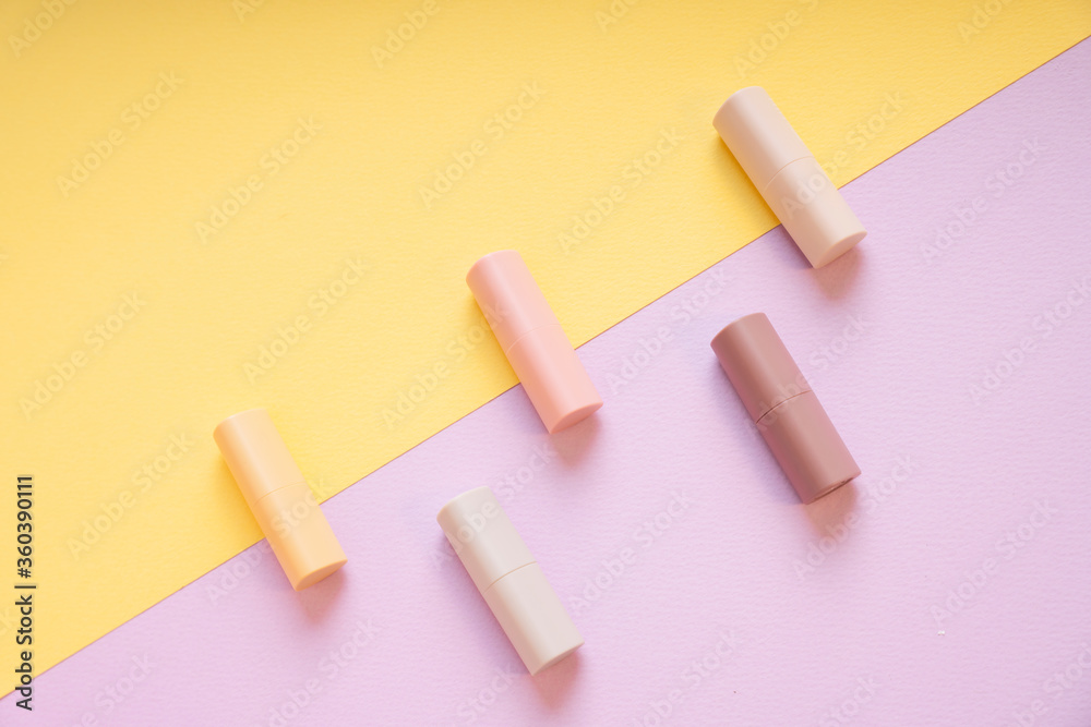 Commercial product - Group of pastel beige lipsticks on yellow and purple background. Commercial product - Group of pastel beige lipsticks on yellow and purple background.