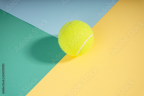 Top view - tennis ball on green blue yellow court paper. Sport concept. © THESHOTS.CO