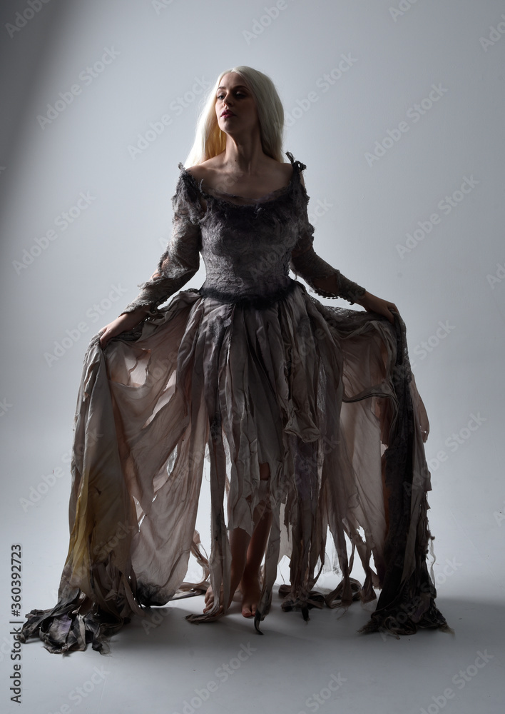 full length portrait of girl wearing old torn wedding dress. standing pose  with rim lighting on a grey studio background. Stock Photo | Adobe Stock