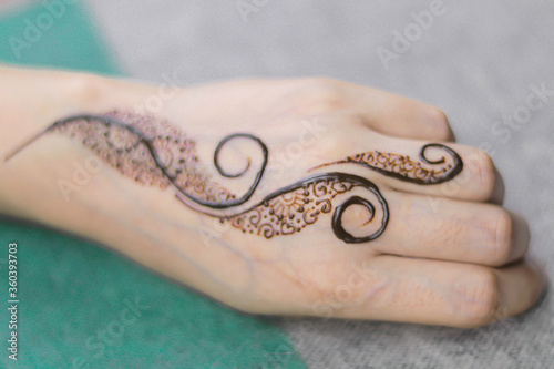 Woman Hands with black mehndi tattoo. Hands of Indian bride girl with black henna tattoos. Hand with perfect turquoise manicure and national Indian jewels. Fashion. India. Marriage traditions