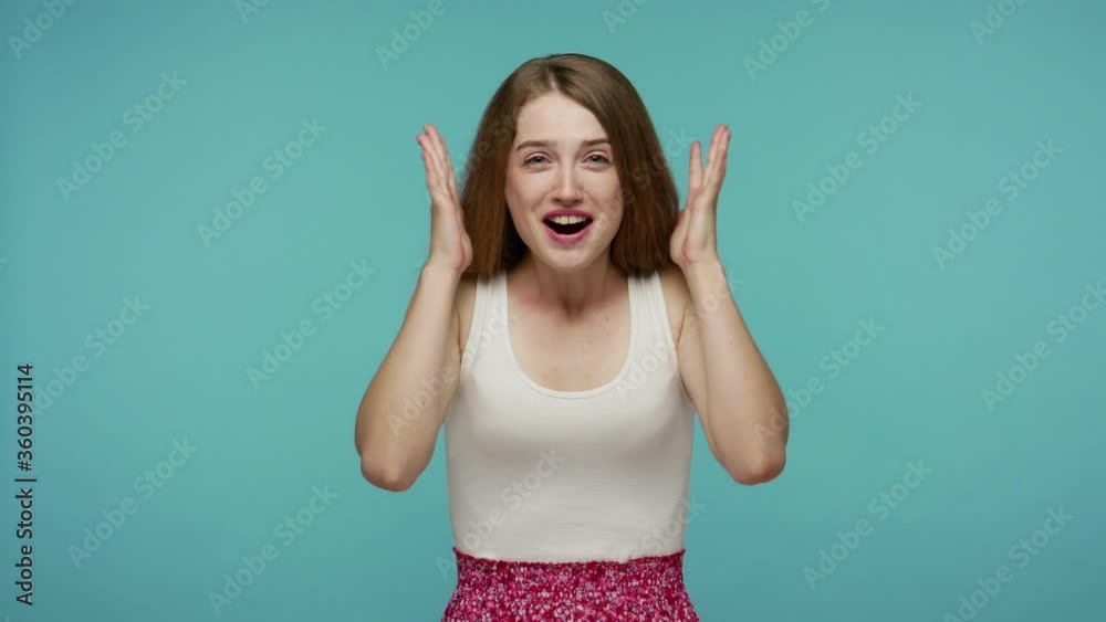 Delighted girl keeping watch unbelievable winning in lottery, raising hands cheering for victory, opening her mouth in amazement, looking surprised shocked. studio shot isolated on blue background Delighted girl keeping watch unbelievable winning in lottery, raising hands cheering for victory, opening her mouth in amazement, looking surprised shocked. studio shot isolated on blue background