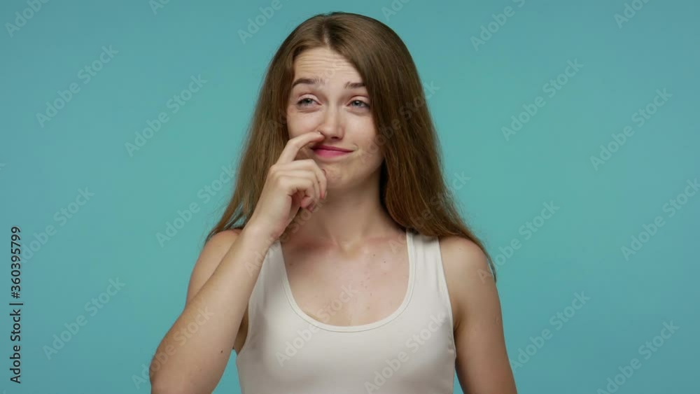 Funny stupid carefree girl picking nose and sticking out tongue with silly brainless humorous expression, removing boogers, uncultured habit, bad manners. studio shot isolated on blue background Funny stupid carefree girl picking nose and sticking out tongue with silly brainless humorous expression, removing boogers, uncultured habit, bad manners. studio shot isolated on blue background