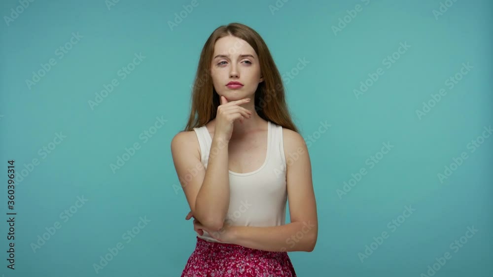 Pensive smart girl rubbing chin and smirking while thinking over idea, imagining plan in mind, having doubts about answer, contemplating and pondering answer. studio shot isolated on blue background Pensive smart girl rubbing chin and smirking while thinking over idea, imagining plan in mind, having doubts about answer, contemplating and pondering answer. studio shot isolated on blue background