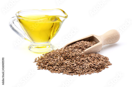 Raw flax seeds in wooden scoop and flaxseed oil in glass gravy boat isolated on white background. Full depth of field with clipping path.