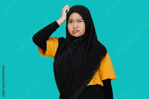 Asian Teen girl wearing headscraf/hijab holding her head feel confused with close her eye photo