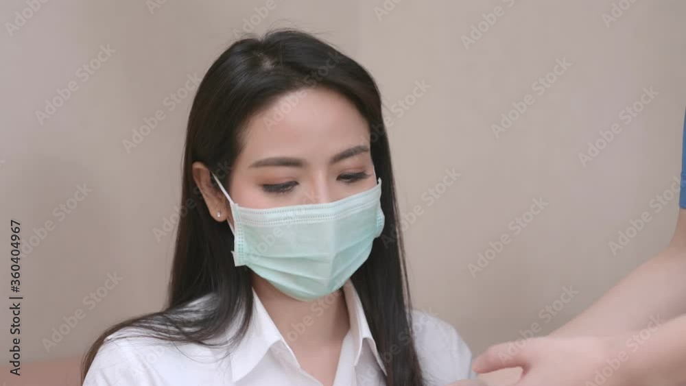 Asian female patients wear face mask being measured for fever with a digital thermometer from a nurse in the hospital. Asian female patients wear face mask being measured for fever with a digital thermometer from a nurse in the hospital.