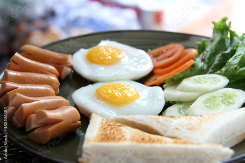 American breakfast with fried eggs, sausages, toasts and fresh salad with blur background
