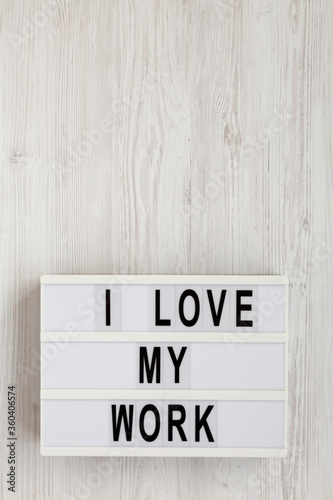 Fototapeta Naklejka Na Ścianę i Meble -  'I love my work' words on a lightbox on a white wooden surface, top view. Flat lay, from above, overhead. Copy space.