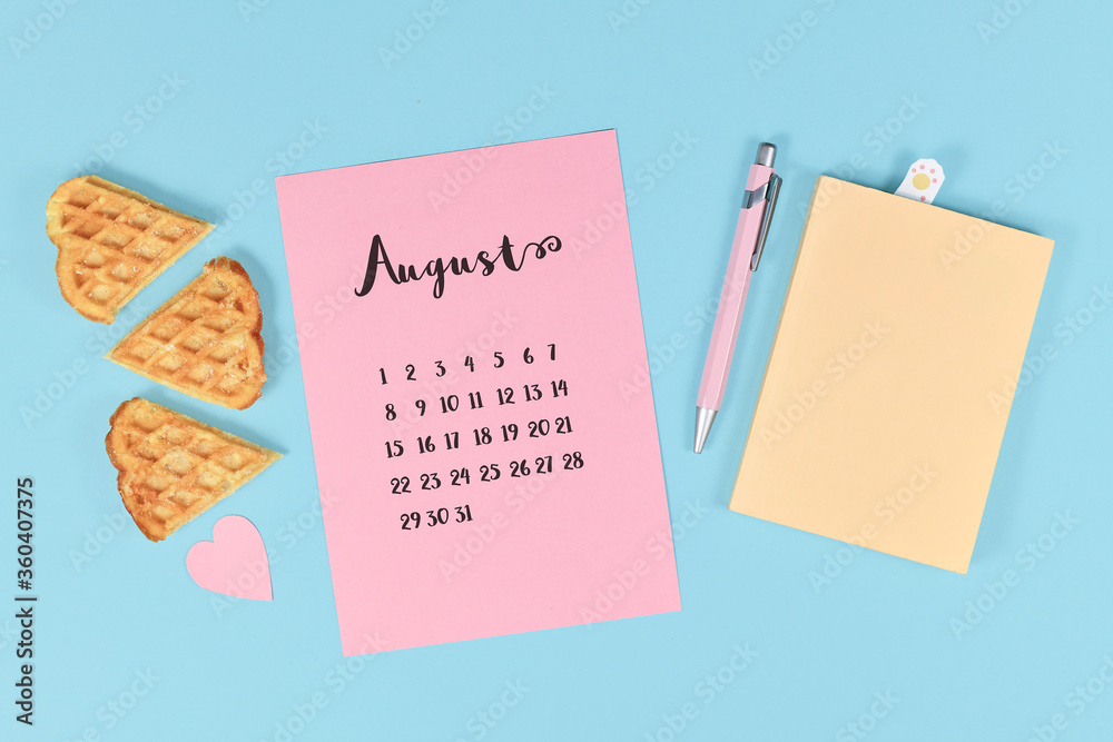 August month concept with pink calendar sheet, book, pen, paper heart and waffle pieces on ight blue background August month concept with pink calendar sheet, book, pen, paper heart and waffle pieces on ight blue background