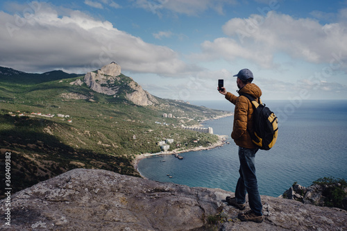 man taking photo of awesome view of mountains with smartphone