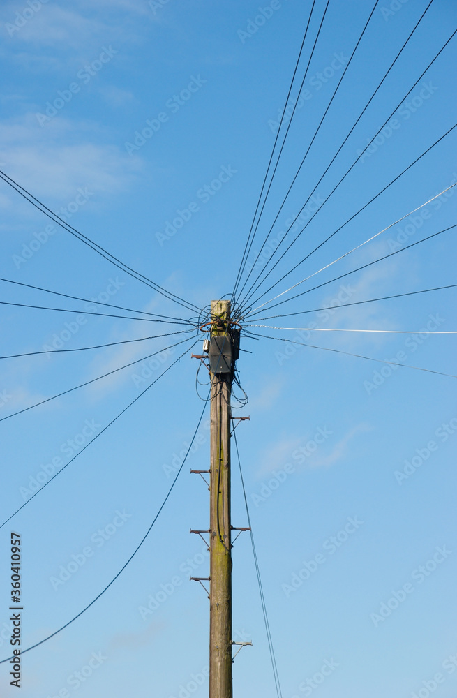 Telegraph pole with radiating telephone cables against a blue sky Telegraph pole with radiating telephone cables against a blue sky