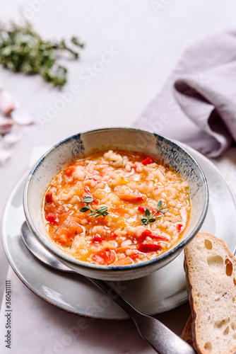 Vegetarian spicy tomato rice soup on grey concrete background. Selective focus