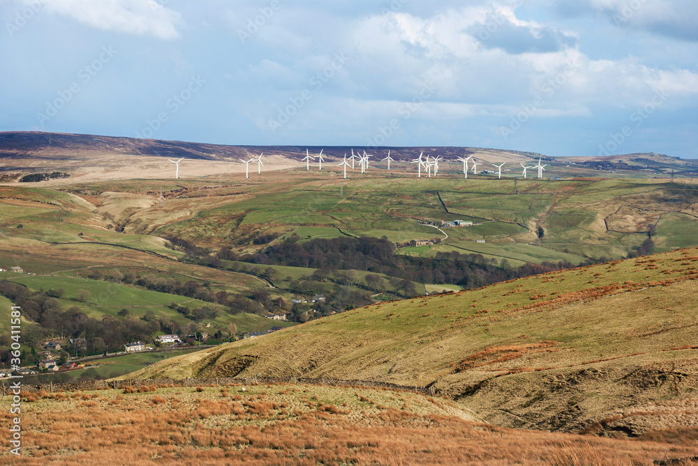 Windmills of a renewable energy wind farm stand in a high moorland landscape in the Pennine hills, Lancashire, England