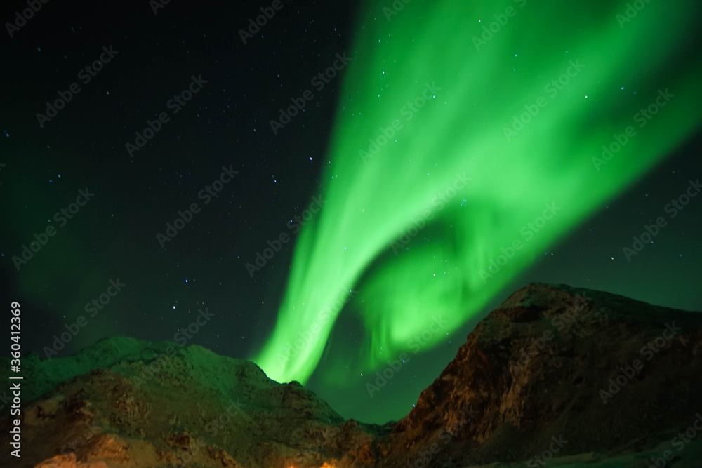 grainy green aurora northern light in the sky at mountain peak in Lofoten Islands with clear sky in winter season