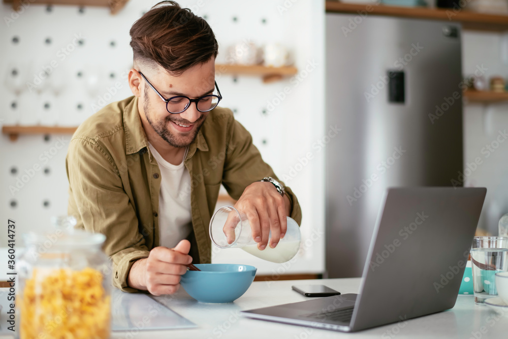 Young man eating breakfast and reading the news online. Handsome man enjoying at home. Young man eating breakfast and reading the news online. Handsome man enjoying at home.